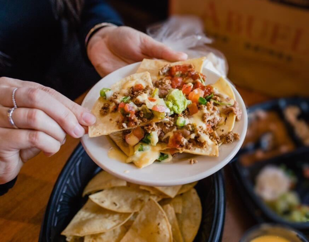 Abuelo's customer holding a plate of nachos