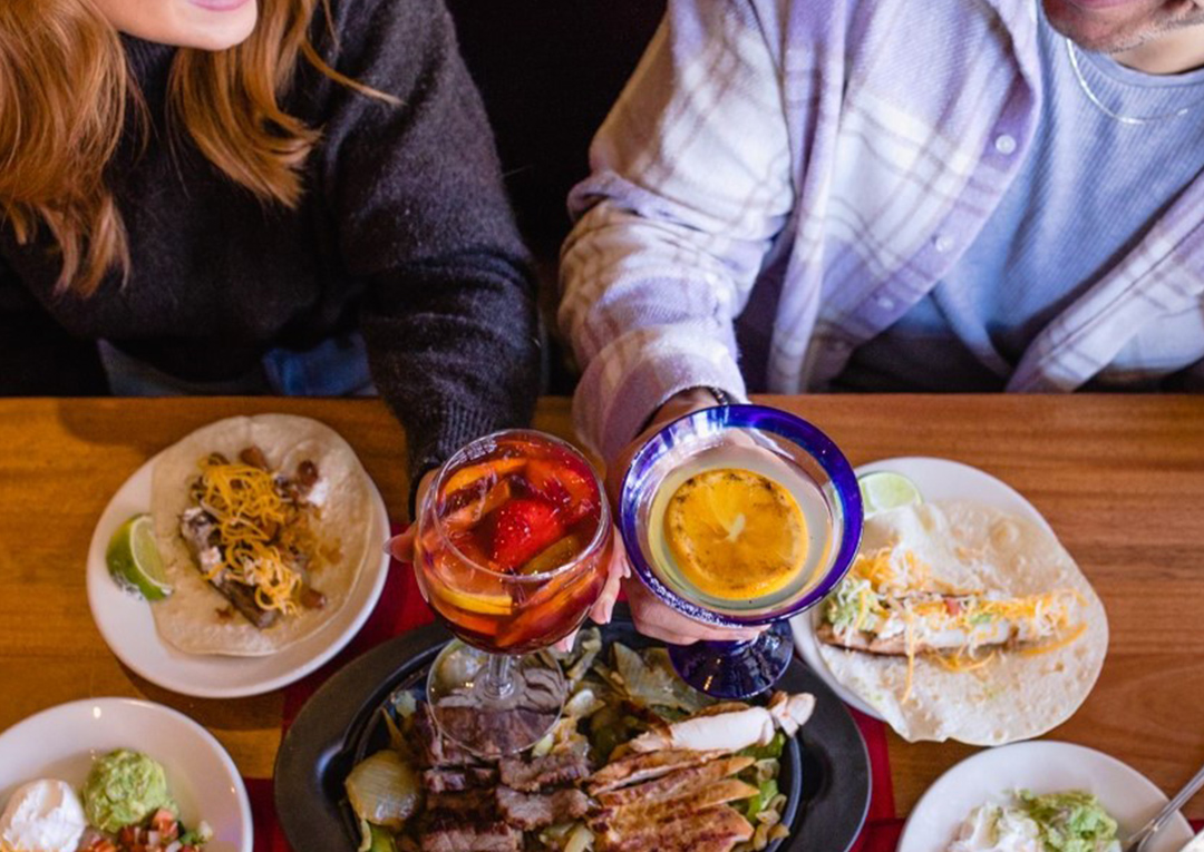 Two Abuelo's guests holding drinks glasses