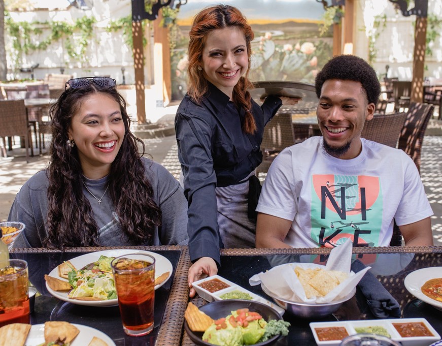 Server presenting food to guests dining outdoors at Abuelo's